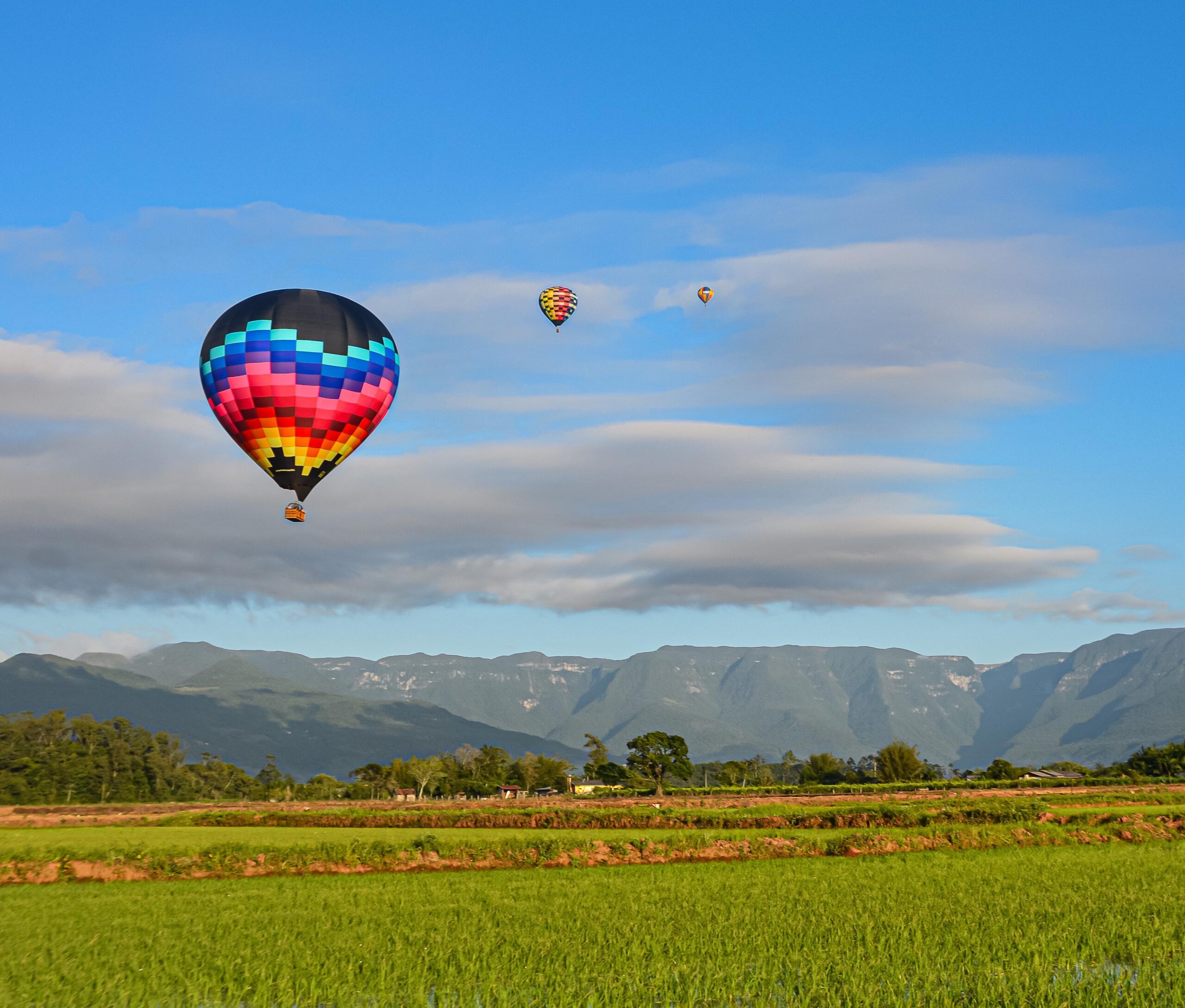 Três balões no ar com o céu ao fundo, nuvens e canyons