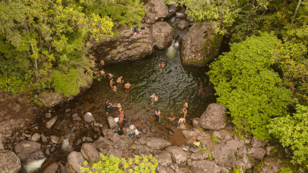 Pessoas em um rio, rodeadas por pedras e árvores