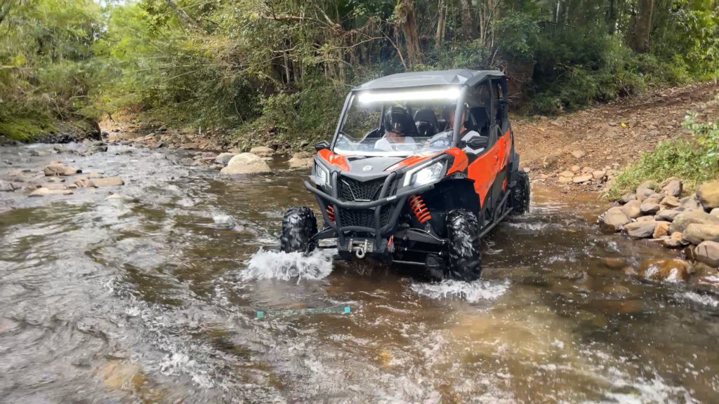 UTV andando sobre rio com água rasa após uma trilha de terra